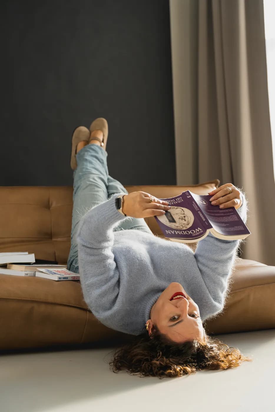 Monika czyta magazyn, leżąc do góry nogami na kanapie